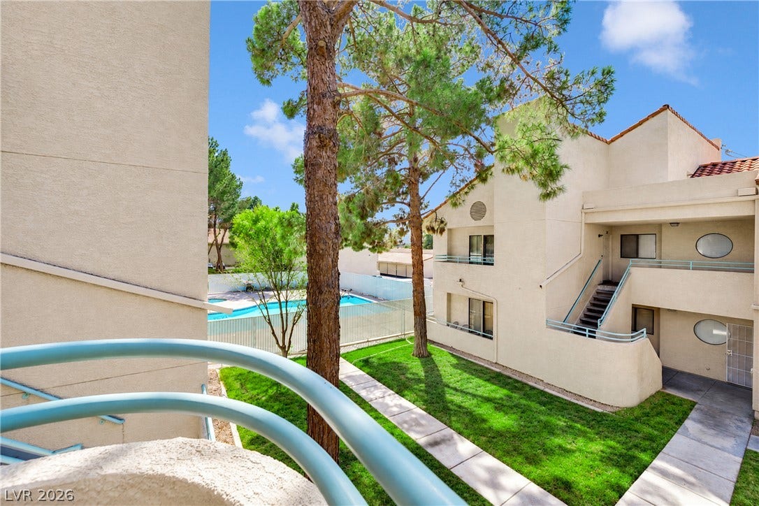 Mature trees and paved walkways frame the central courtyard outside this multi-level residential building.