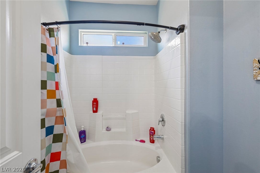An inviting bathtub with a shower head and clean white tile surround provides a serene bathing experience.