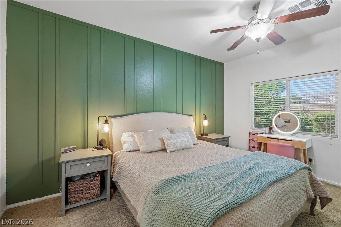 A well-lit bedroom with a vibrant accent wall and ample natural light. Located downstairs