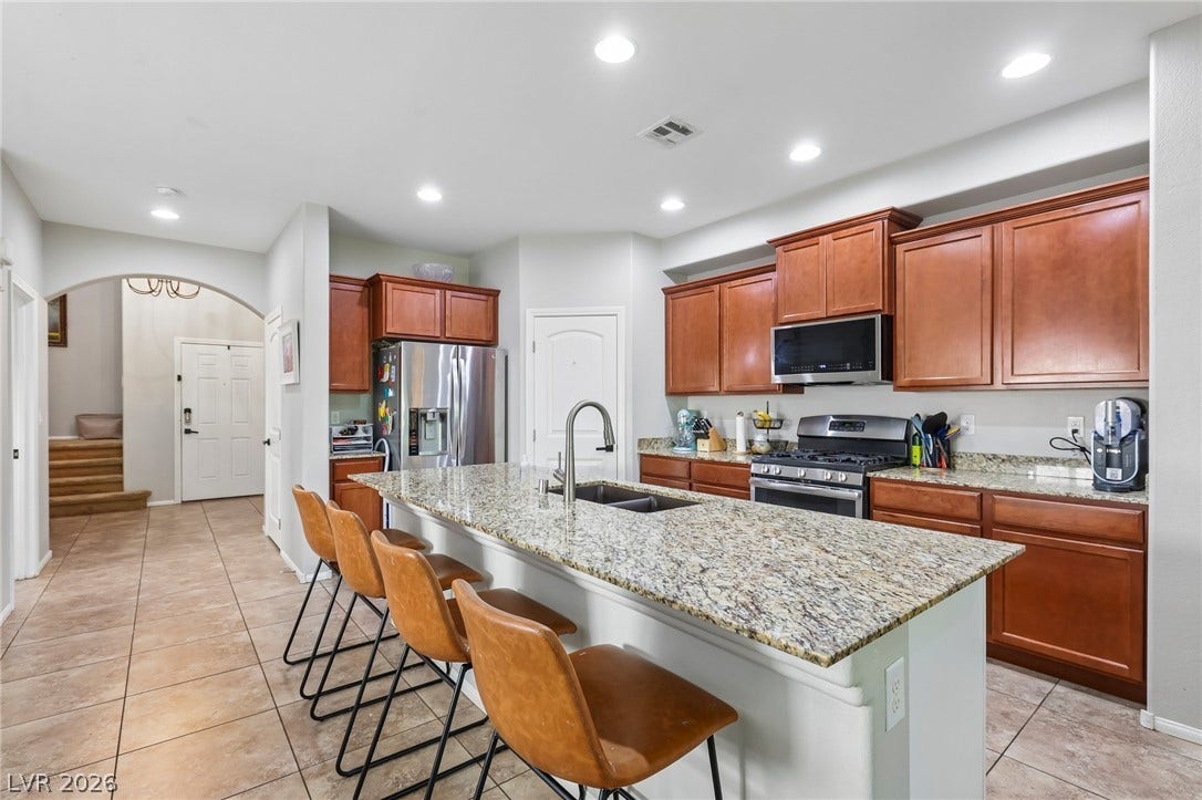 An inviting kitchen with a spacious granite island and rich wood cabinetry, perfect for entertaining.