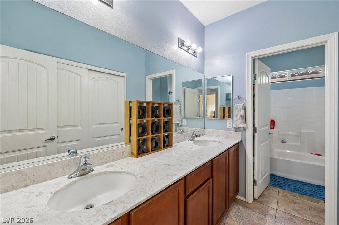 Double vanity with stone counters provides ample space in this well-appointed primary bathroom.
