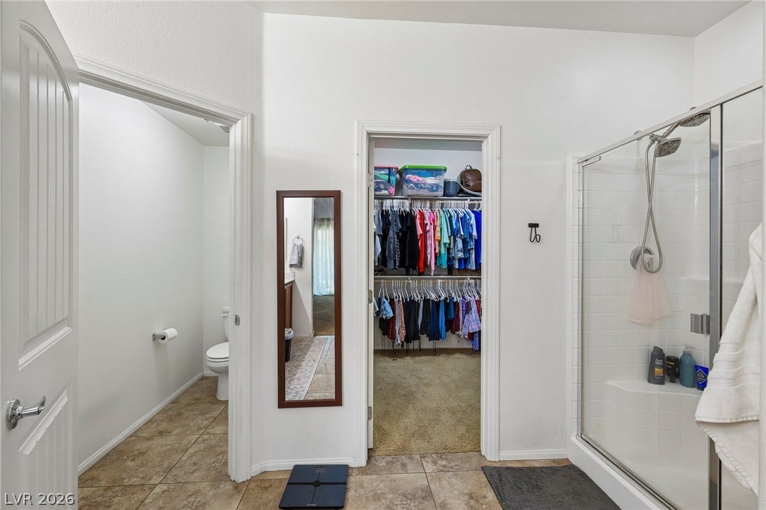 Functional bathroom features a walk-in closet and a clear glass shower for streamlined living.