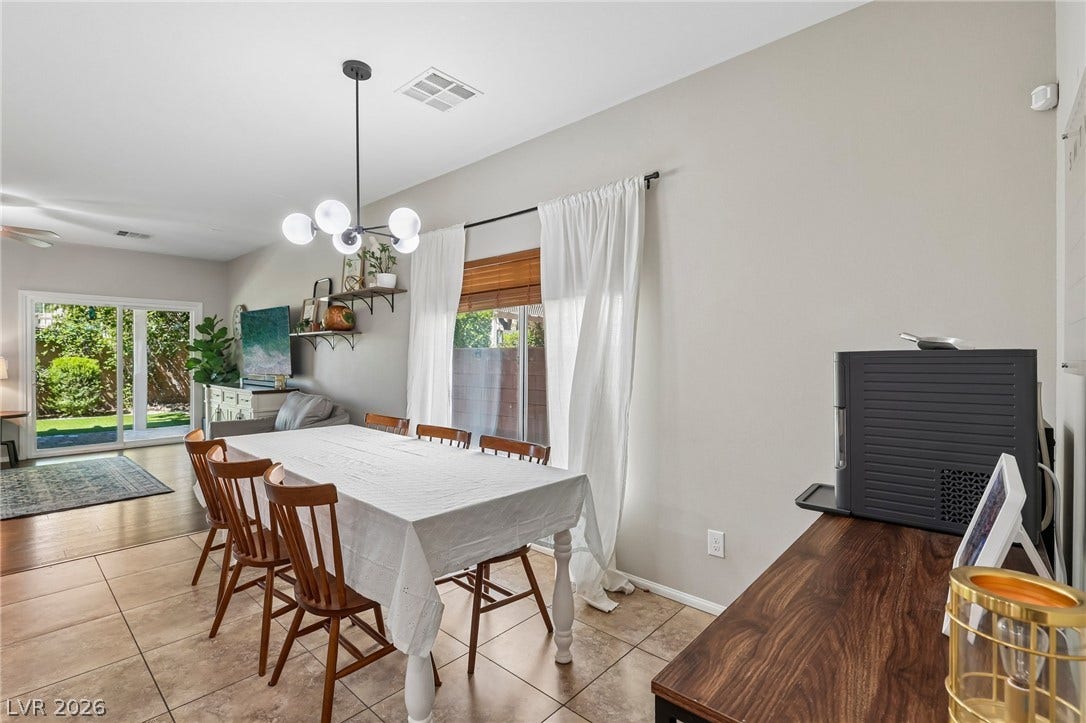 Natural light floods this dining area, featuring practical tile flooring and an elegant contemporary light fixture.