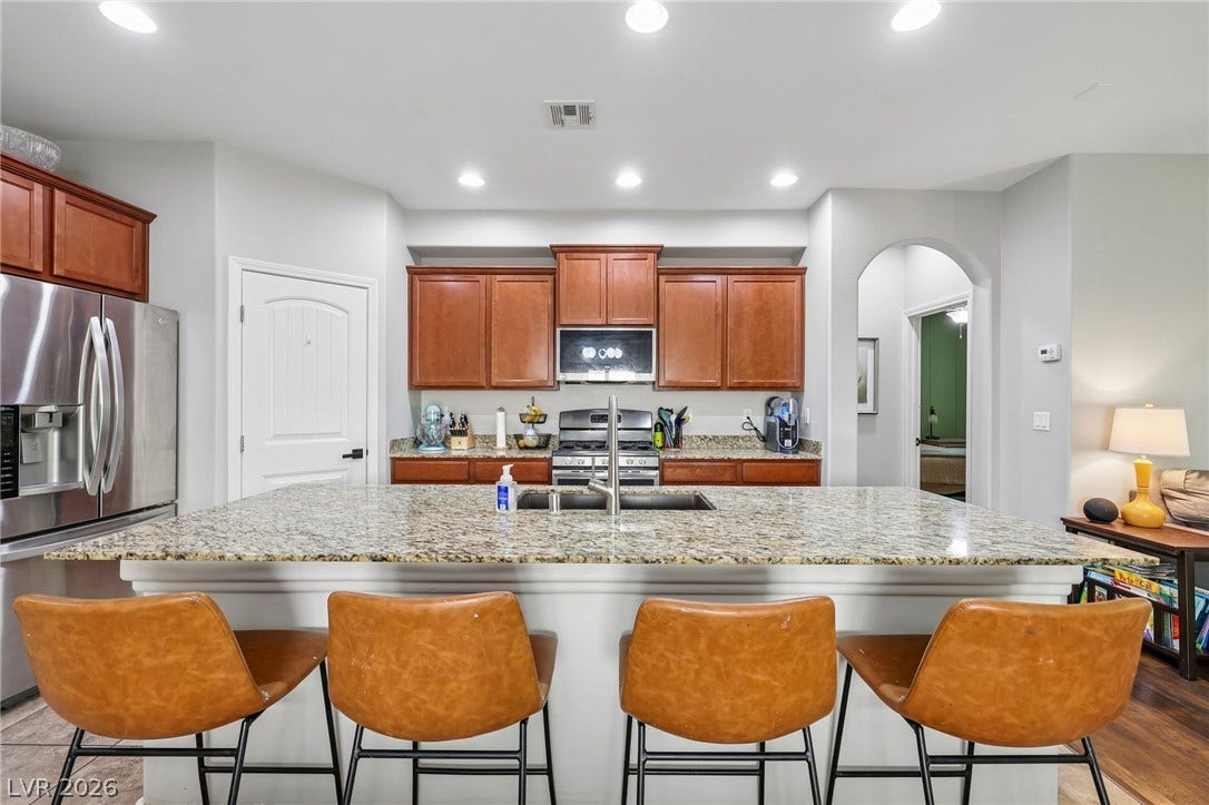 A well-appointed kitchen features a large granite island and stainless steel appliances.