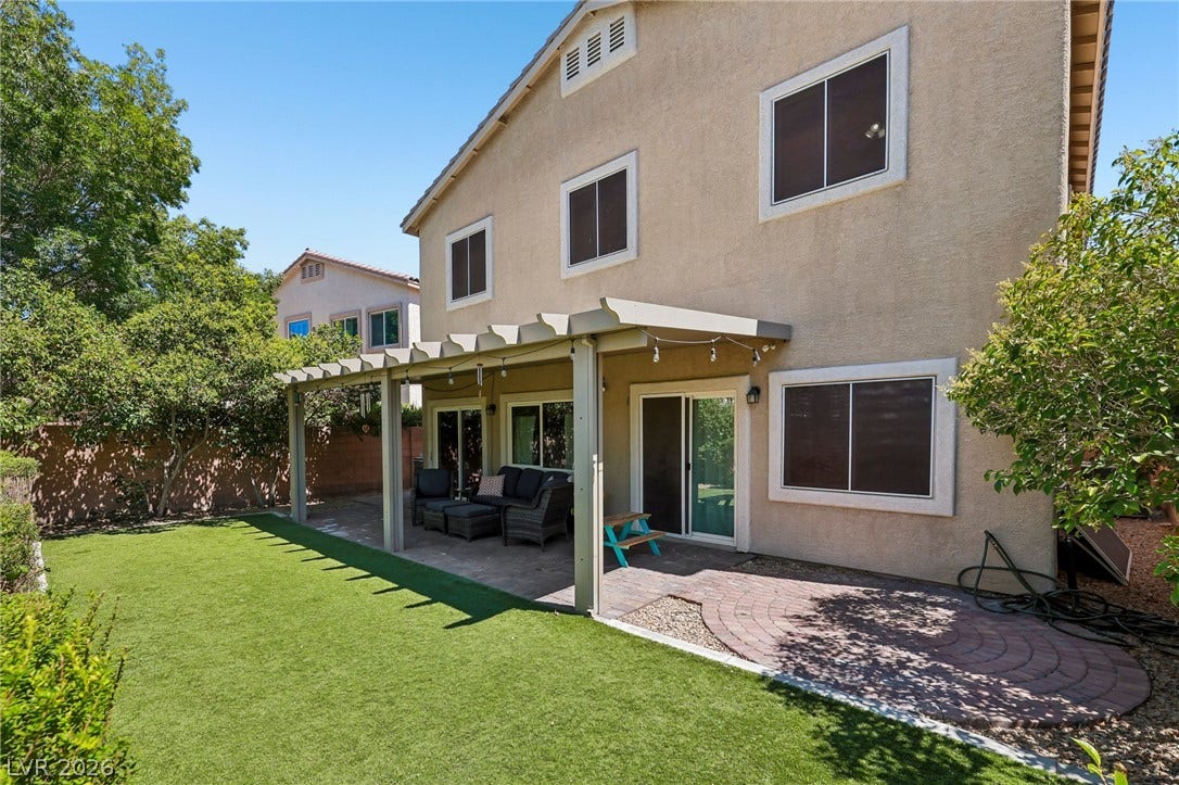 A well-maintained yard offers artificial turf and a shaded patio area, perfect for outdoor enjoyment.