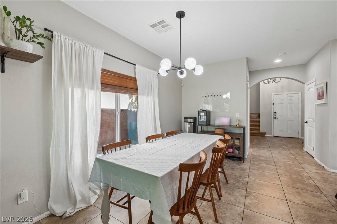 A well-lit dining area featuring a modern chandelier and tiled flooring for easy maintenance.