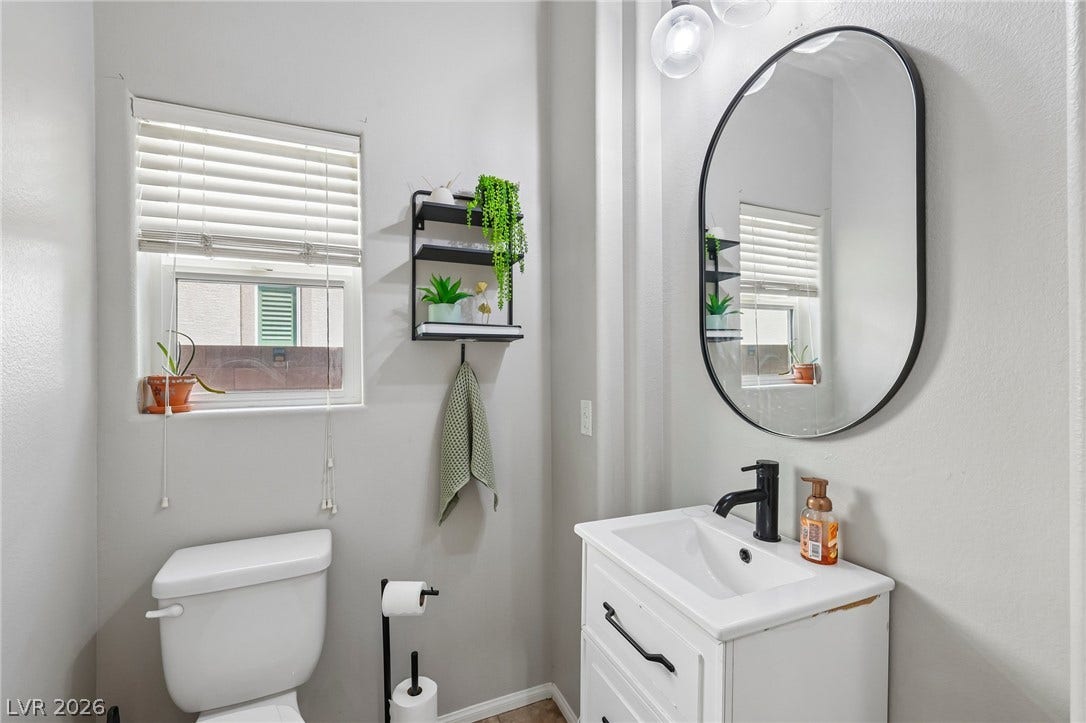 A well-lit powder room offers practical elegance with a modern vanity and essential fixtures.
