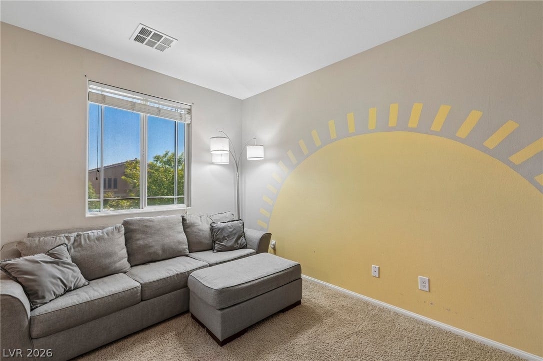 A well-lit bedroom provides ample natural illumination and soft carpeted flooring.