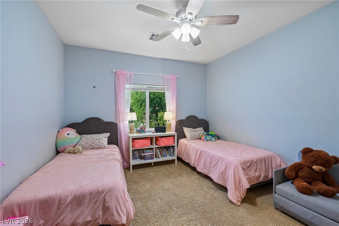 A well-lit bedroom features plush carpeting and a modern ceiling fan, creating a comfortable living space.