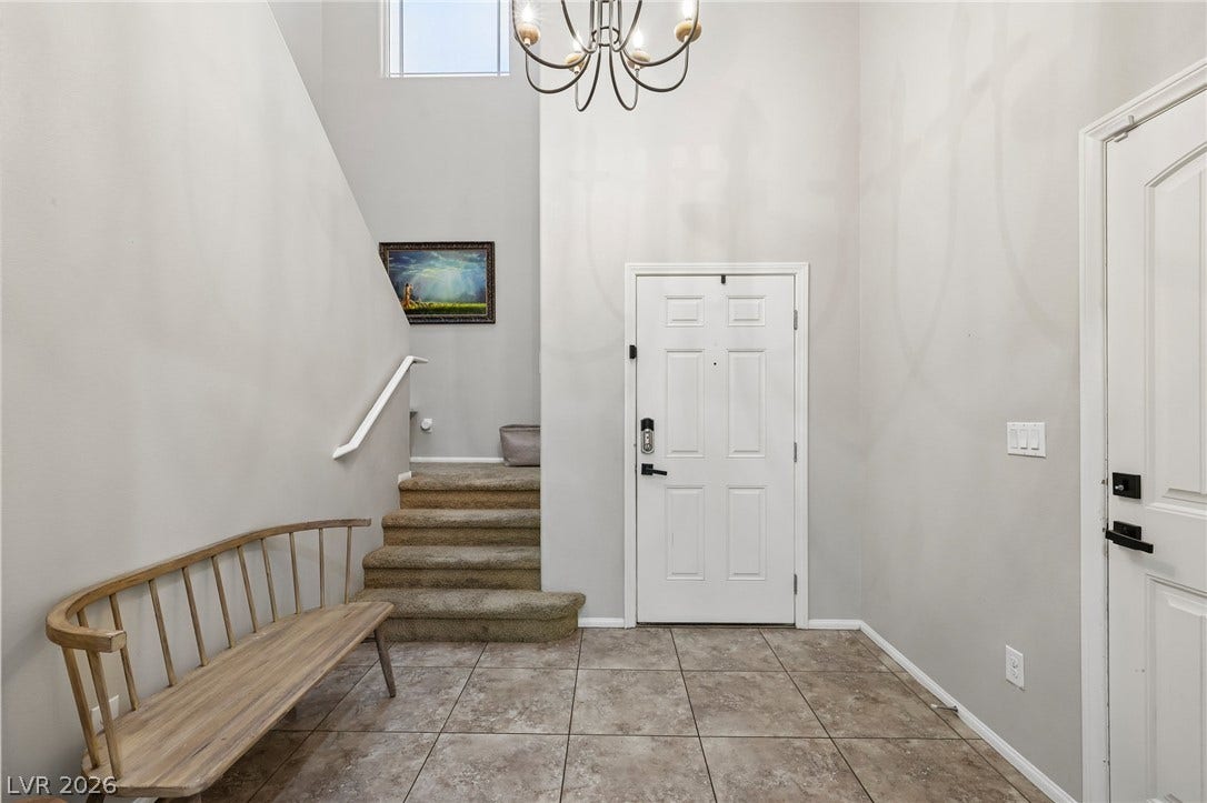 A well-lit entry with a tiled floor and a staircase leading to the upper level.