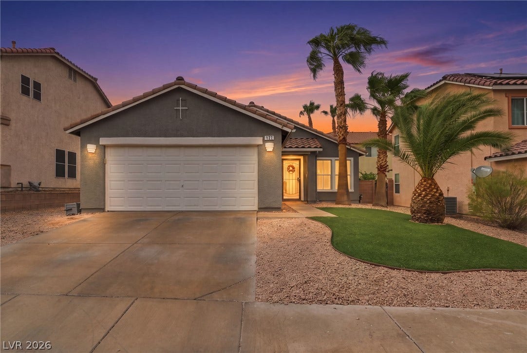 Palm trees accent the neat low-maintenance landscaping and concrete driveway of this stucco home.