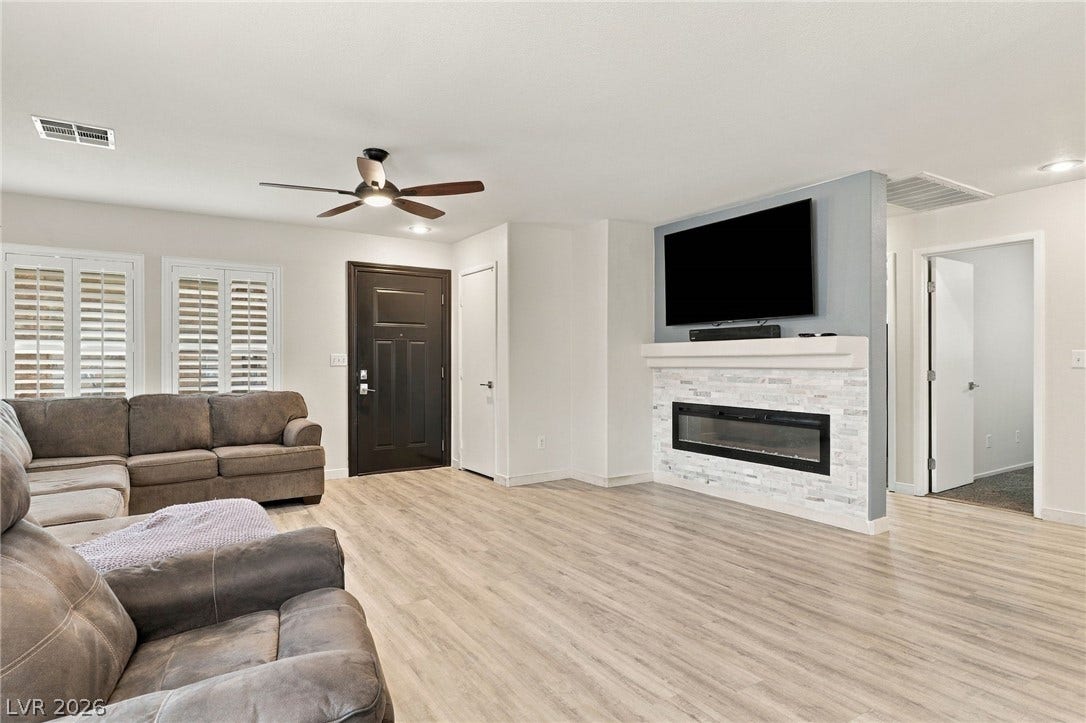 A modern fireplace anchors the open living space styled with wood-finish flooring.