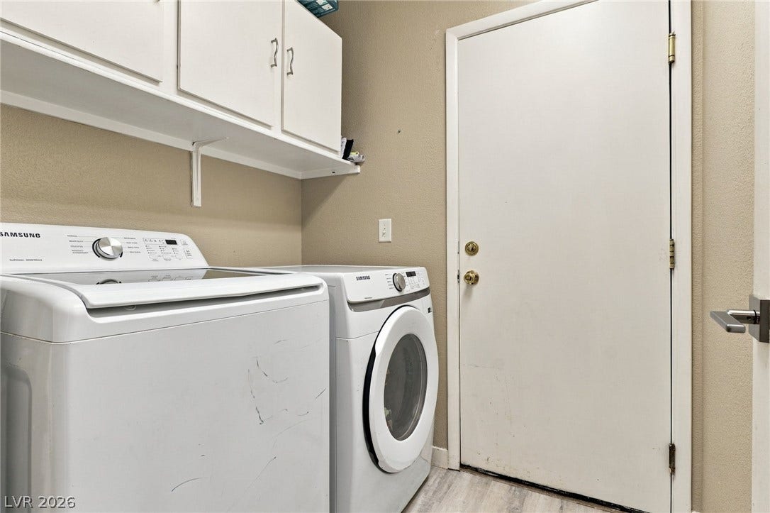 Practical storage cabinets hang above the laundry appliances in this functional utility space.