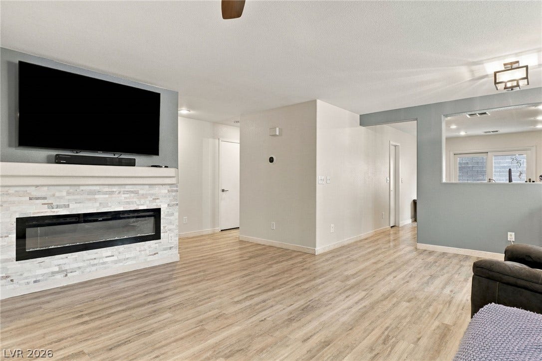 An inviting stone fireplace anchors the living space, seamlessly opening to adjacent rooms.