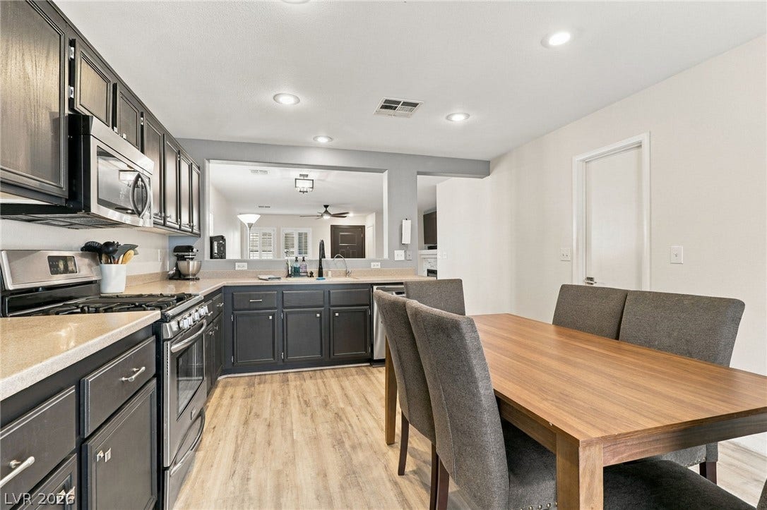 Gleaming wood flooring complements dark cabinetry and stone counters in this functional kitchen layout.