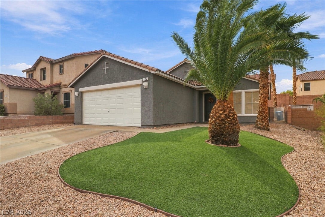 Palm trees accent the low-maintenance front yard of this modern stucco home with tile roofing.
