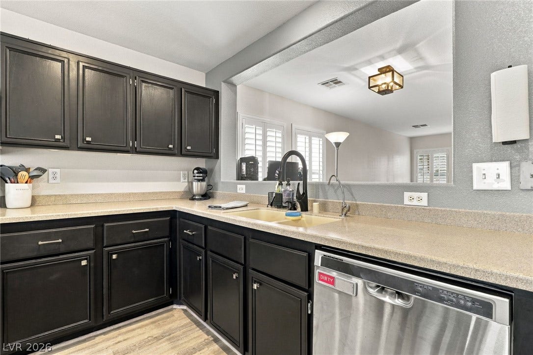 Dark cabinetry and durable counters frame a practical pass-through overlooking the adjacent living area.