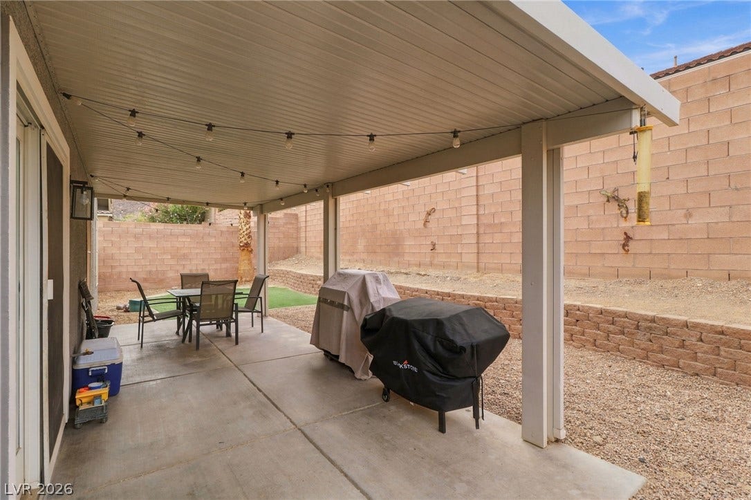 A sheltered concrete patio overlooks a low-maintenance yard enclosed by block privacy walls.