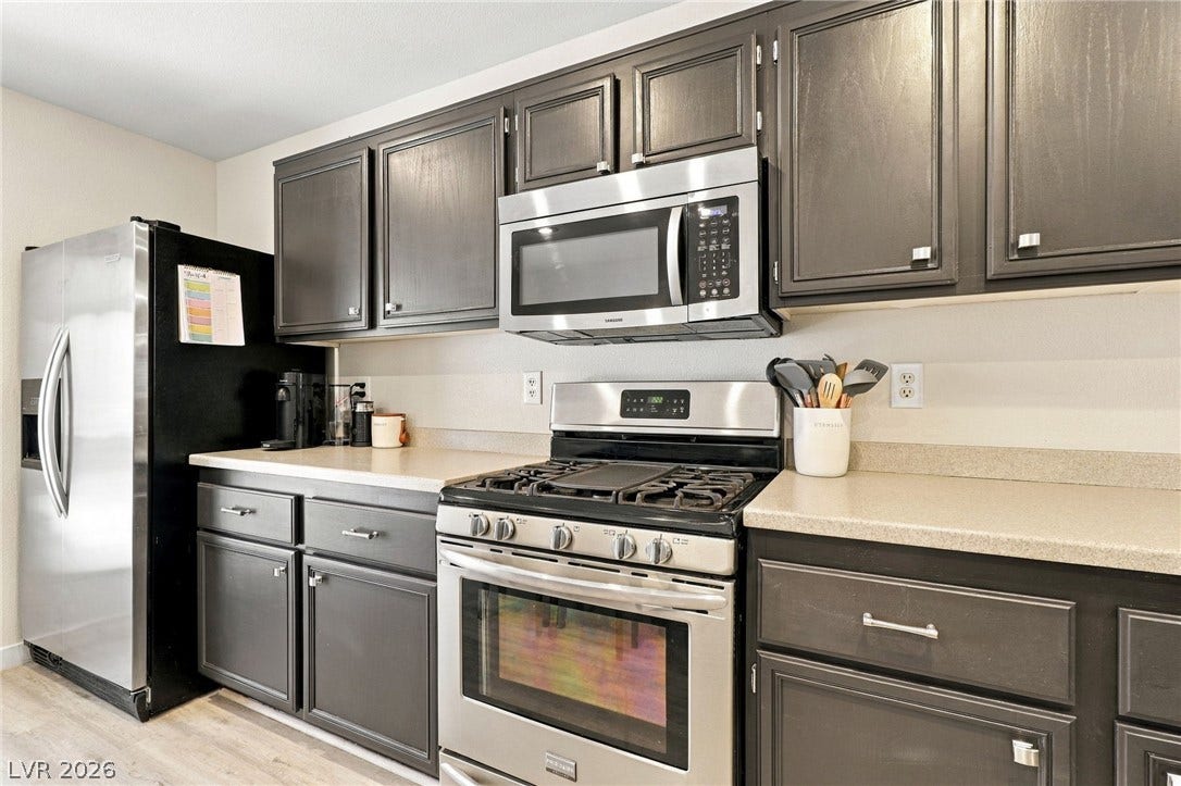 Rich dark cabinetry pairs with durable countertops and stainless steel appliances in this functional kitchen.