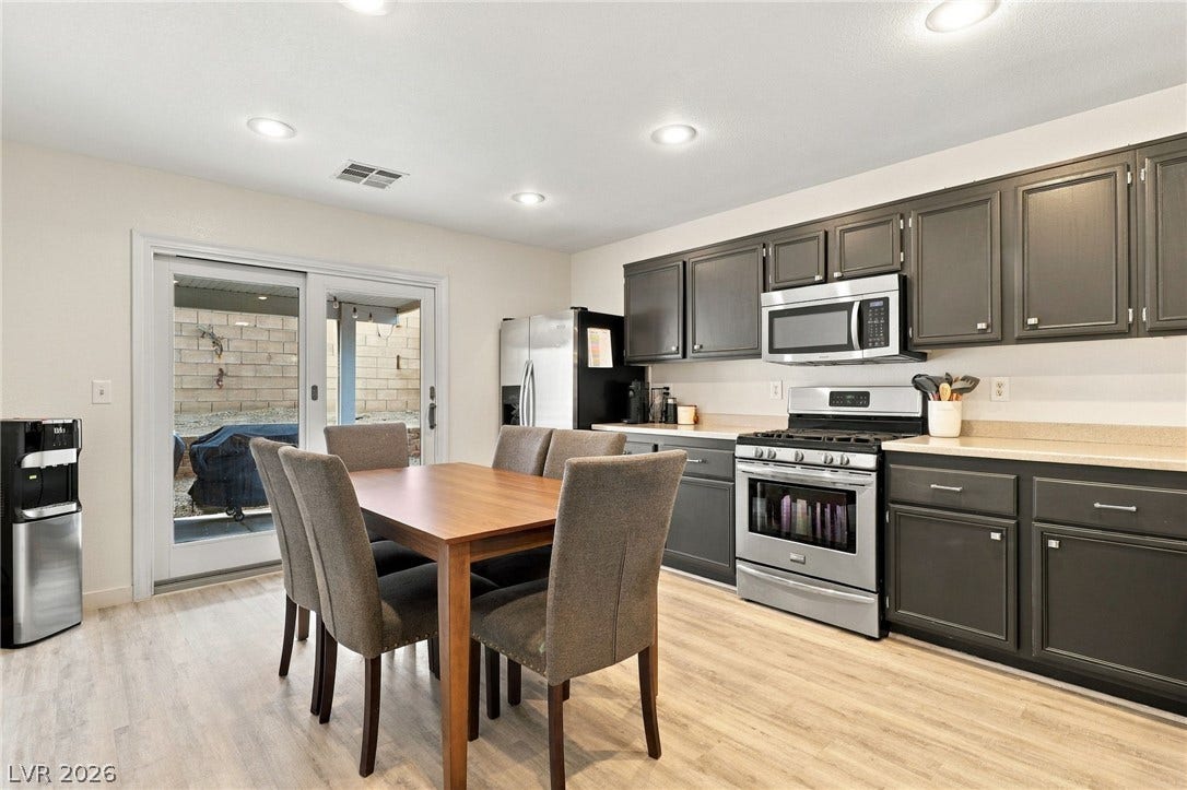 Smooth wood-look flooring and dark cabinetry anchor this open dining and kitchen space.