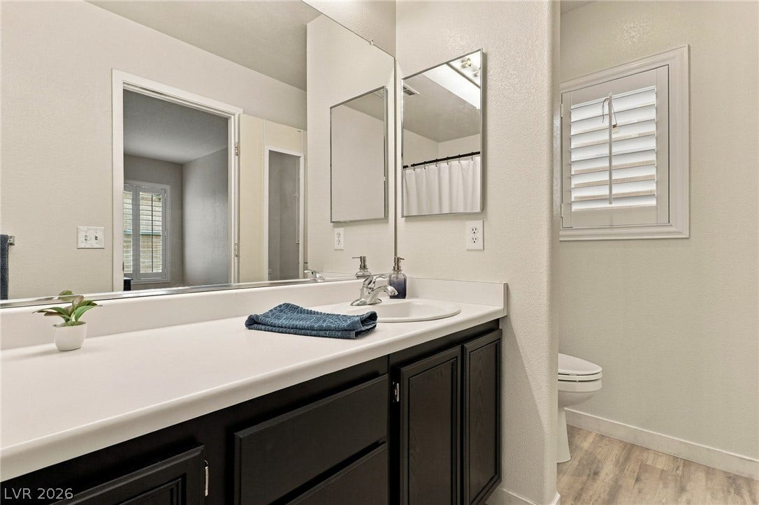 Crisp white countertops contrast beautifully with dark cabinetry beneath an expansive vanity mirror.