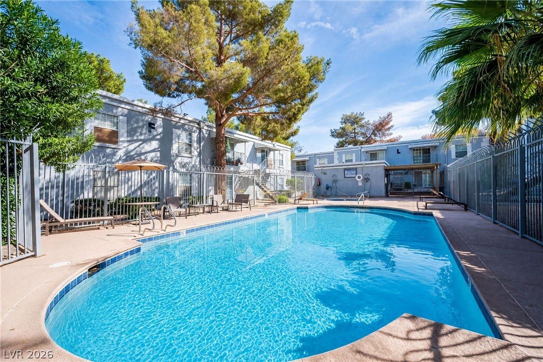 3823 S Maryland Parkway, #B11, Las Vegas, NV 89119 Mature trees frame a sparkling community swimming pool enclosed by security fencing.