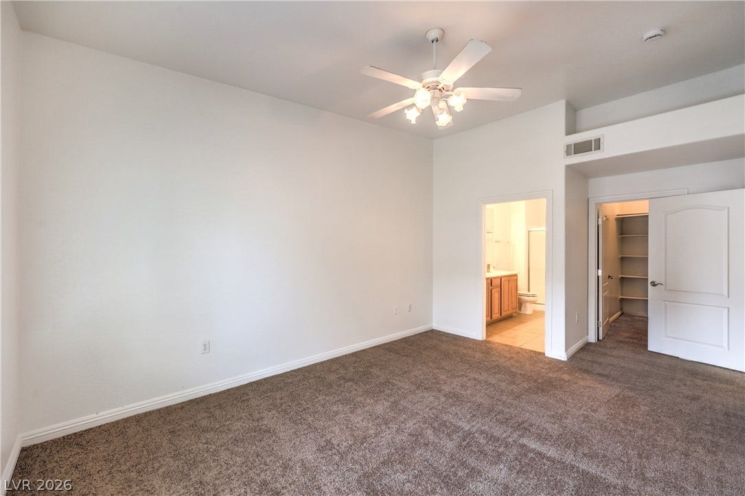 A spacious secondary suite features comfortable carpeted flooring and high ceilings with attached bathroom access.