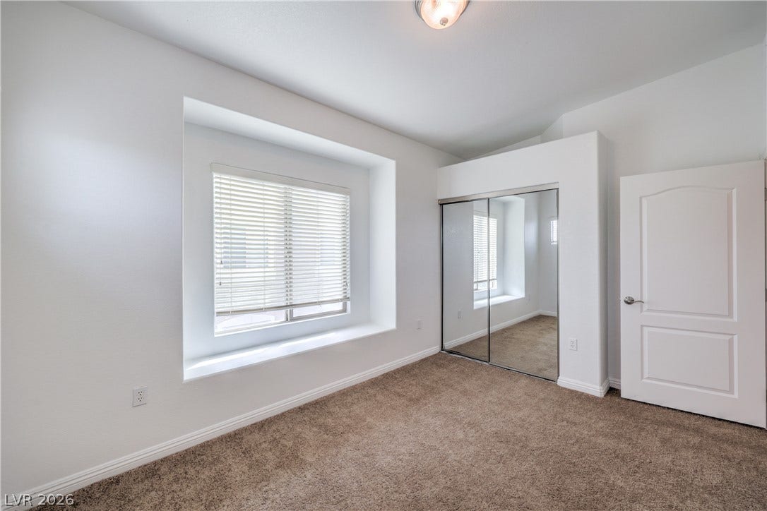 Carpeted flooring and a deep window bench define this comfortable bedroom space.
