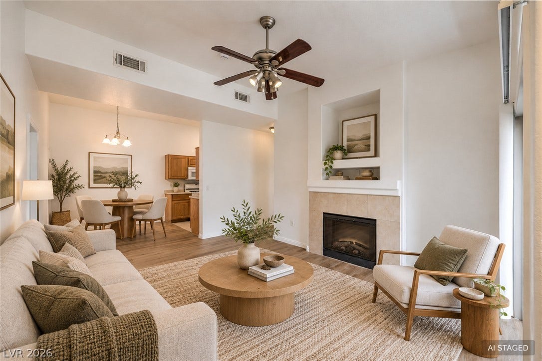 High ceilings and a warm fireplace define this inviting, open-concept living space with wood-style flooring.