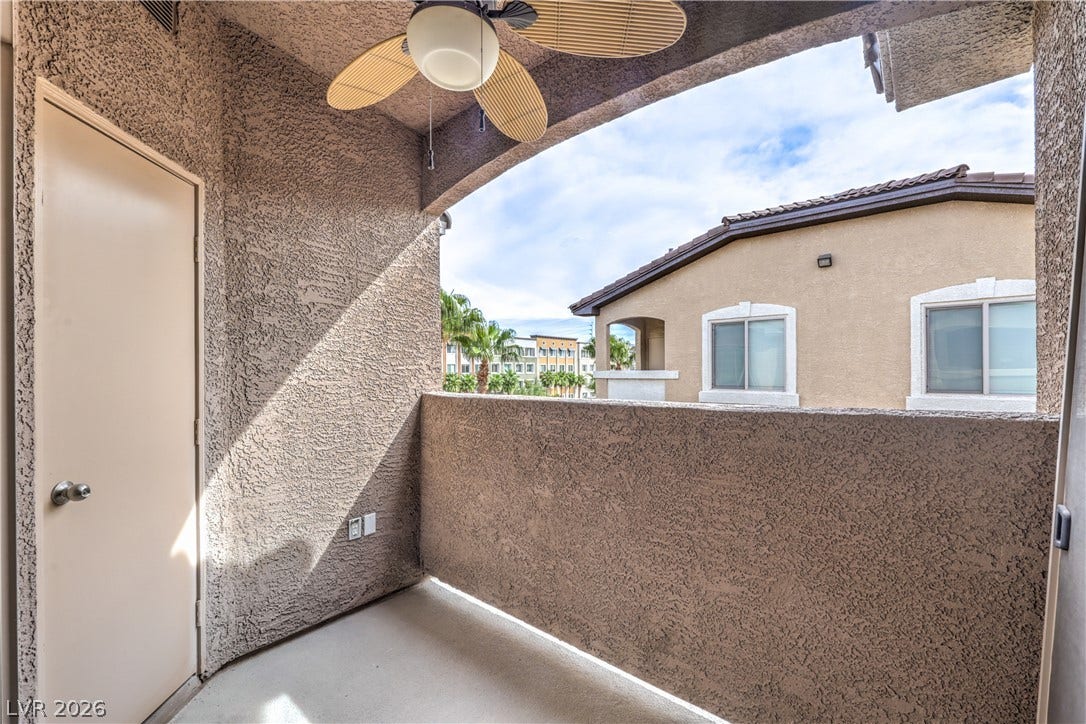 An inviting covered balcony features textured stucco walls and concrete flooring.