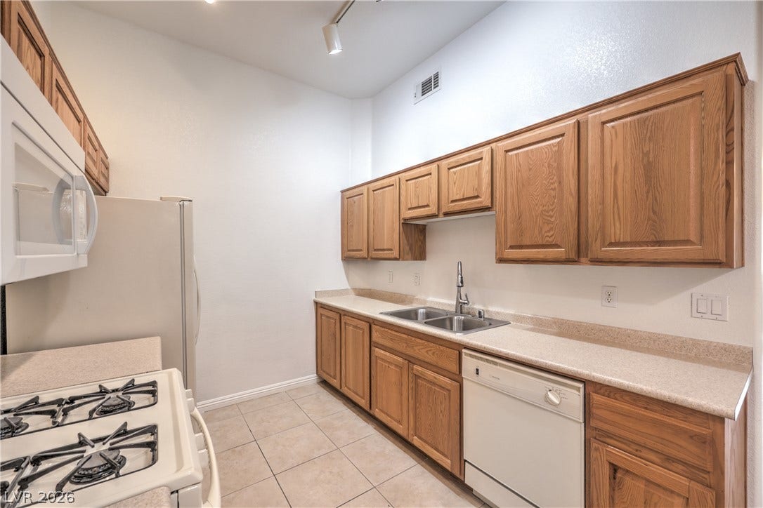 Ample wooden cabinetry and neutral tile flooring define this highly functional kitchen layout.