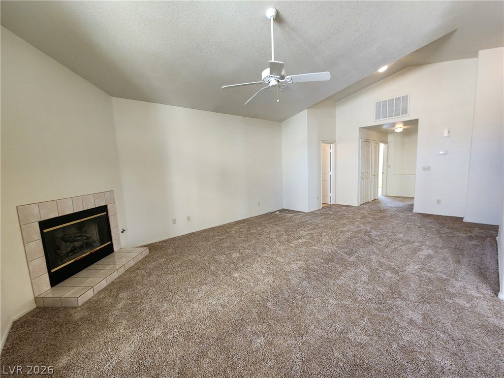 8301 Boseck Drive, #237, Las Vegas, NV 89145 A spacious carpeted living area features vaulted ceilings and a classic tile-trimmed fireplace.