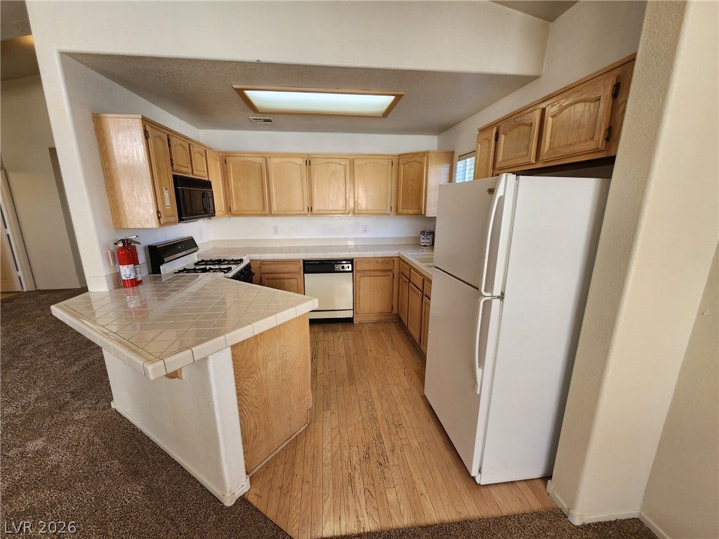8301 Boseck Drive, #237, Las Vegas, NV 89145 Ample wooden cabinetry and classic tile countertops define this functional kitchen space.