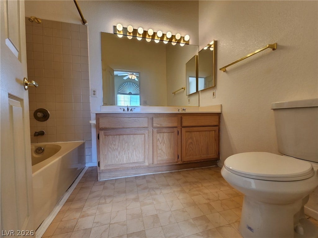 8301 Boseck Drive, #237, Las Vegas, NV 89145 A classic wood vanity and tiled shower tub combo anchor this functional bathroom space.