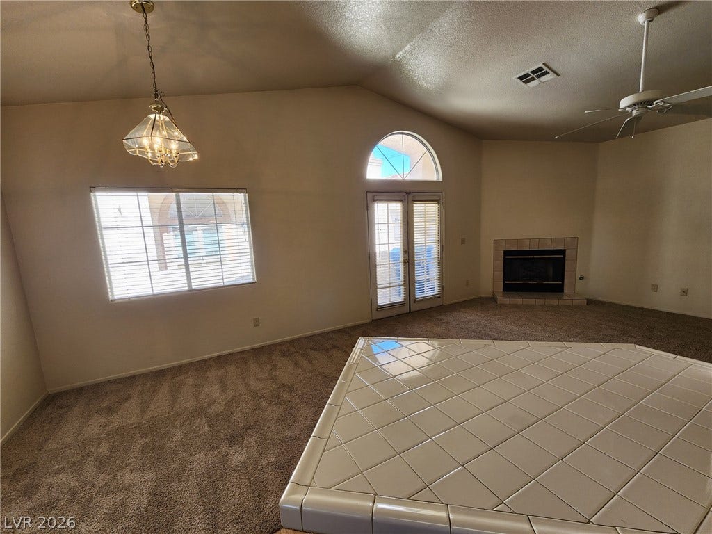 8301 Boseck Drive, #237, Las Vegas, NV 89145 An open living space features vaulted ceilings, a tiled fireplace, and sliding French doors.