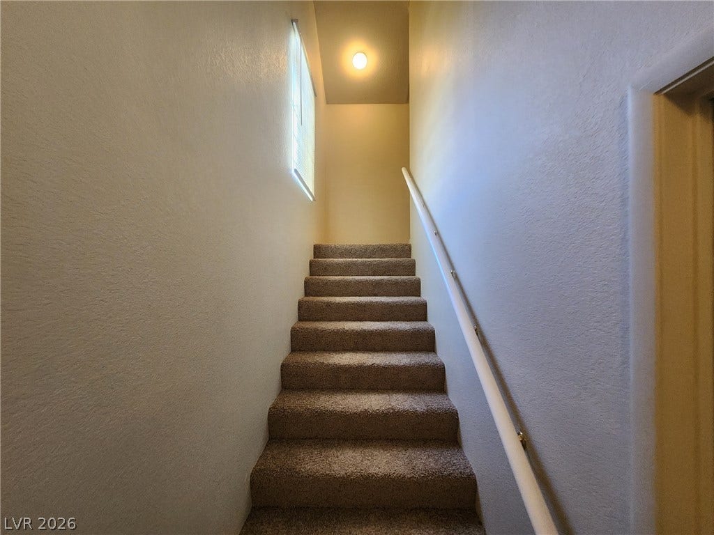 8301 Boseck Drive, #237, Las Vegas, NV 89145 Carpeted stairs ascend alongside a sturdy handrail, illuminated by a natural window and overhead light.