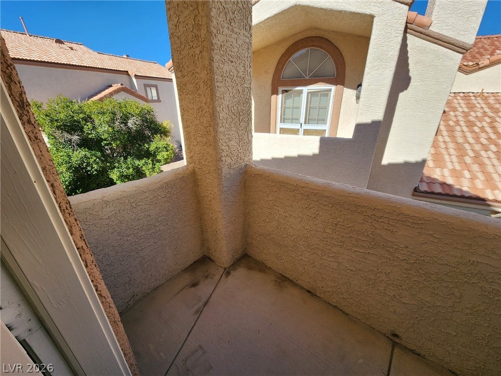 8301 Boseck Drive, #237, Las Vegas, NV 89145 Stucco pillars frame a private balcony overlooking neighborhood trees and tiled roofs.