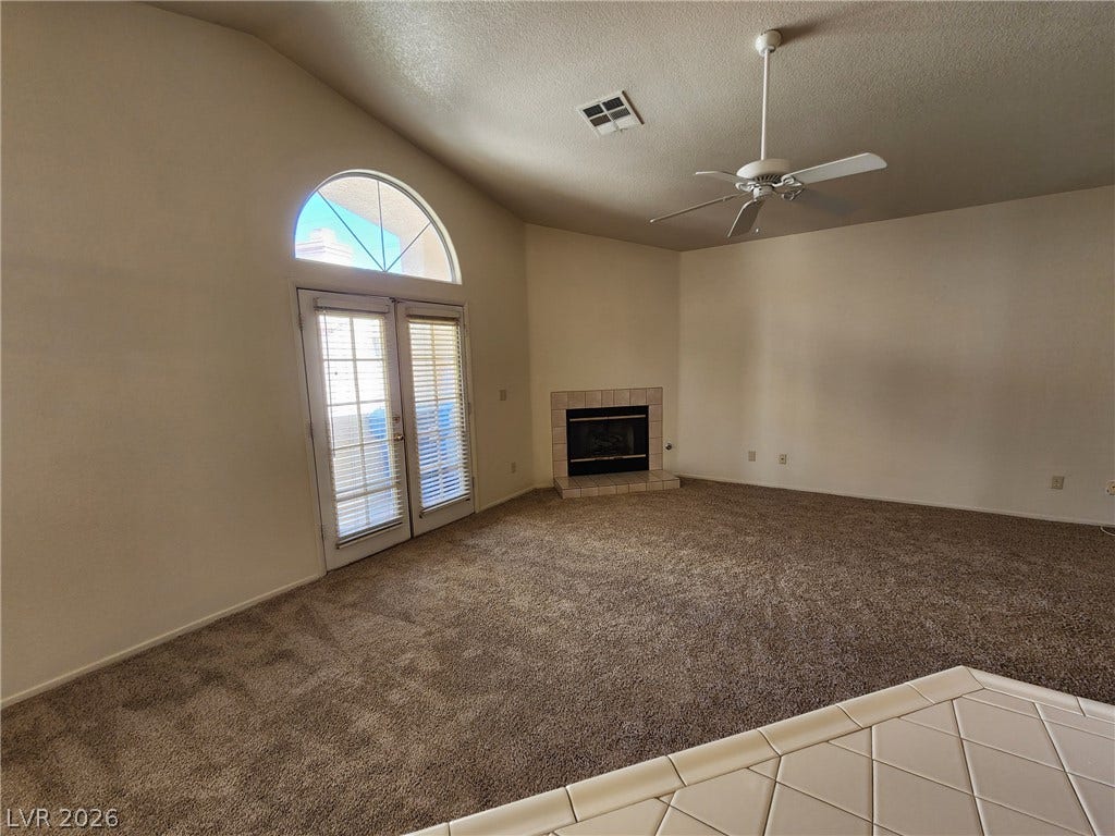 8301 Boseck Drive, #237, Las Vegas, NV 89145 An arched transom window tops double glass doors in a carpeted living space with fireplace.