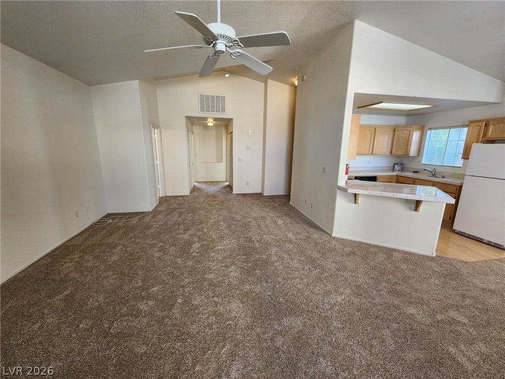 8301 Boseck Drive, #237, Las Vegas, NV 89145 An open floorplan connects the carpeted living area to the kitchen under vaulted ceilings.