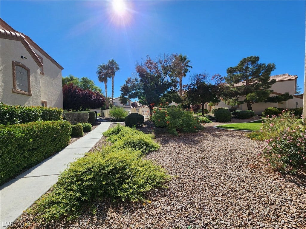 8301 Boseck Drive, #237, Las Vegas, NV 89145 A paved concrete walkway winds through beautifully landscaped desert plantings under a clear blue sky.