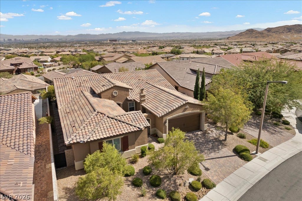 286 Besame Court, Las Vegas, NV 89138 An aerial perspective showcases a tiled roof residence overlooking a desert mountain landscape.