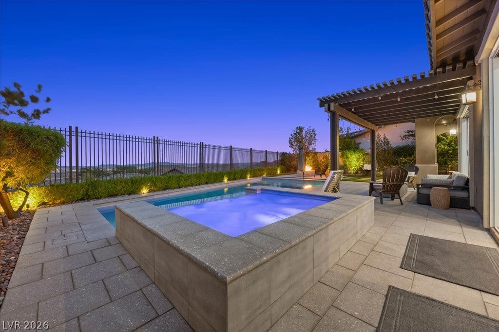 286 Besame Court, Las Vegas, NV 89138 An inviting stone patio surrounds the custom pool and integrated spa under a wooden pergola.