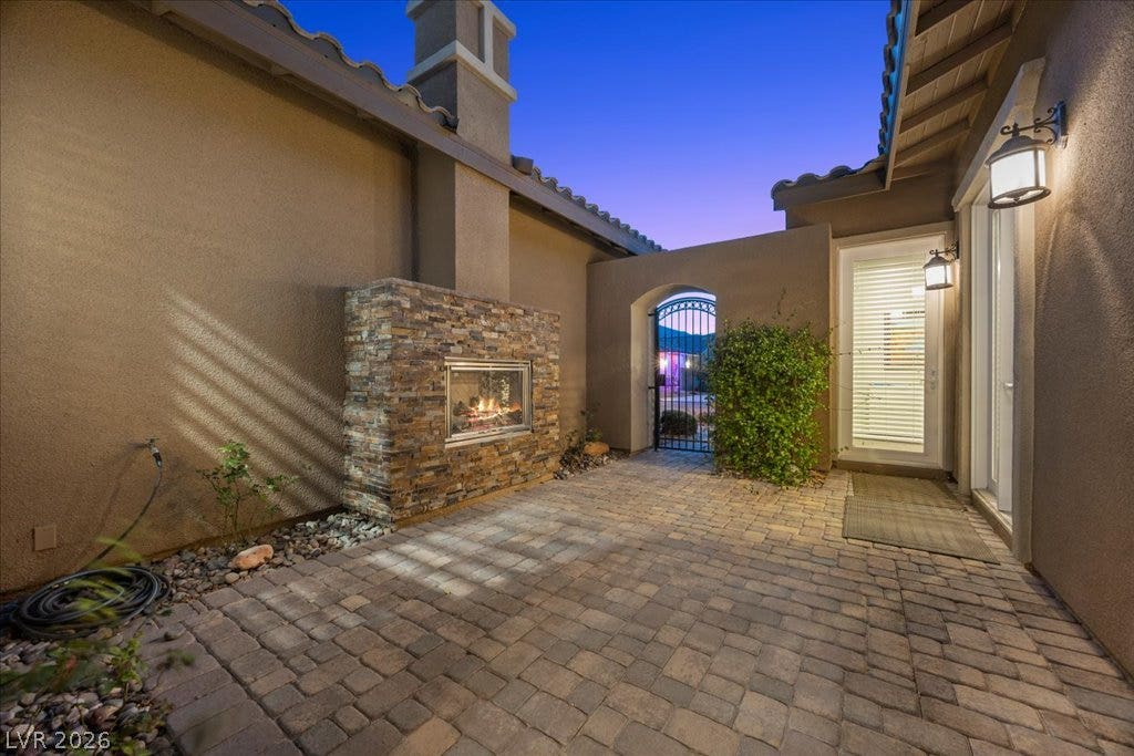286 Besame Court, Las Vegas, NV 89138 An inviting stone-paved courtyard features a cozy outdoor fireplace and a secure arched gate.