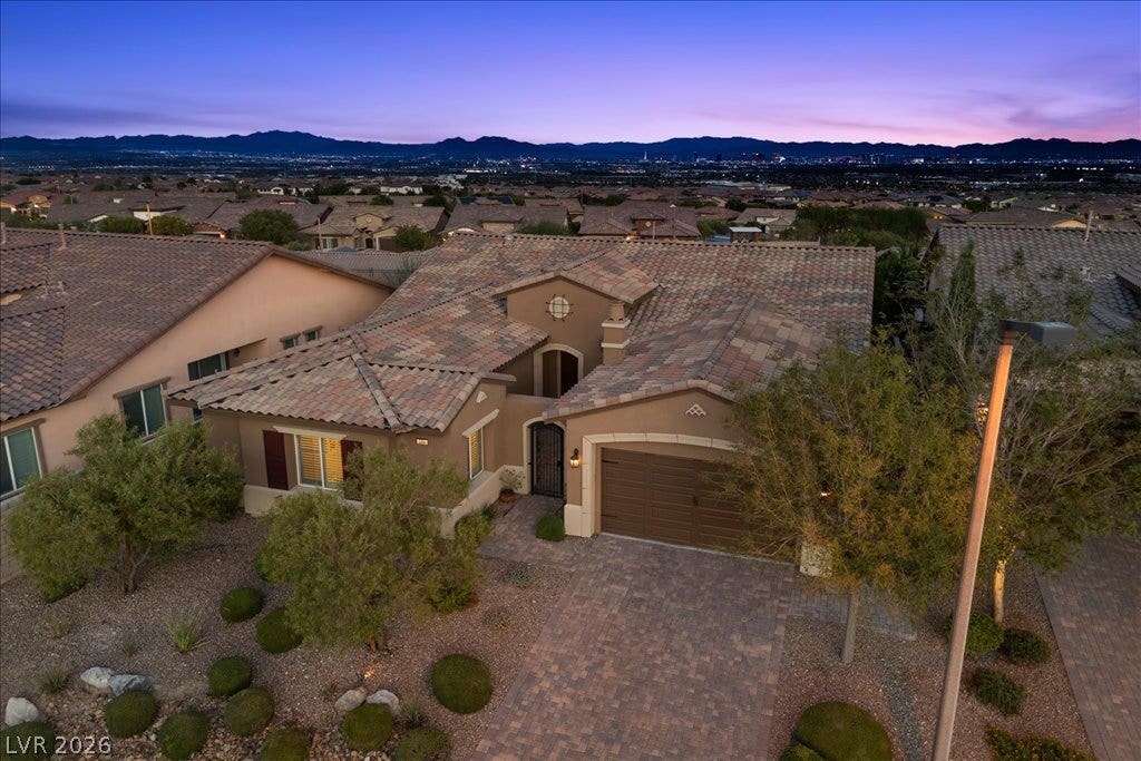 286 Besame Court, Las Vegas, NV 89138 Distant mountains frame this desert home featuring a tiled roof and paver driveway.