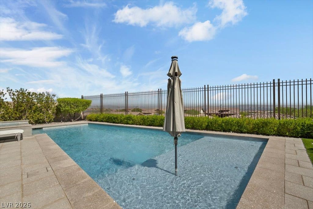 286 Besame Court, Las Vegas, NV 89138 An inviting swimming pool is bordered by stone pavers and protective iron fencing under sunny skies.
