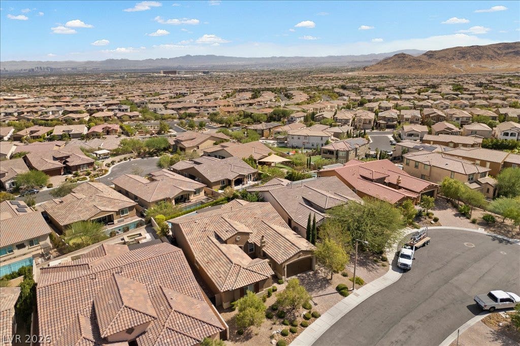 286 Besame Court, Las Vegas, NV 89138 An aerial perspective showcases a suburban residential neighborhood nestled against a desert mountain backdrop.
