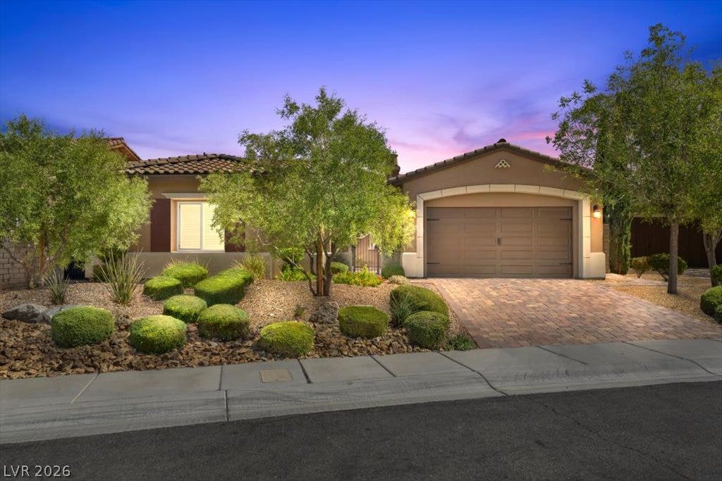 286 Besame Court, Las Vegas, NV 89138 Manicured desert landscaping frames a paved driveway leading to the classic stucco facade.