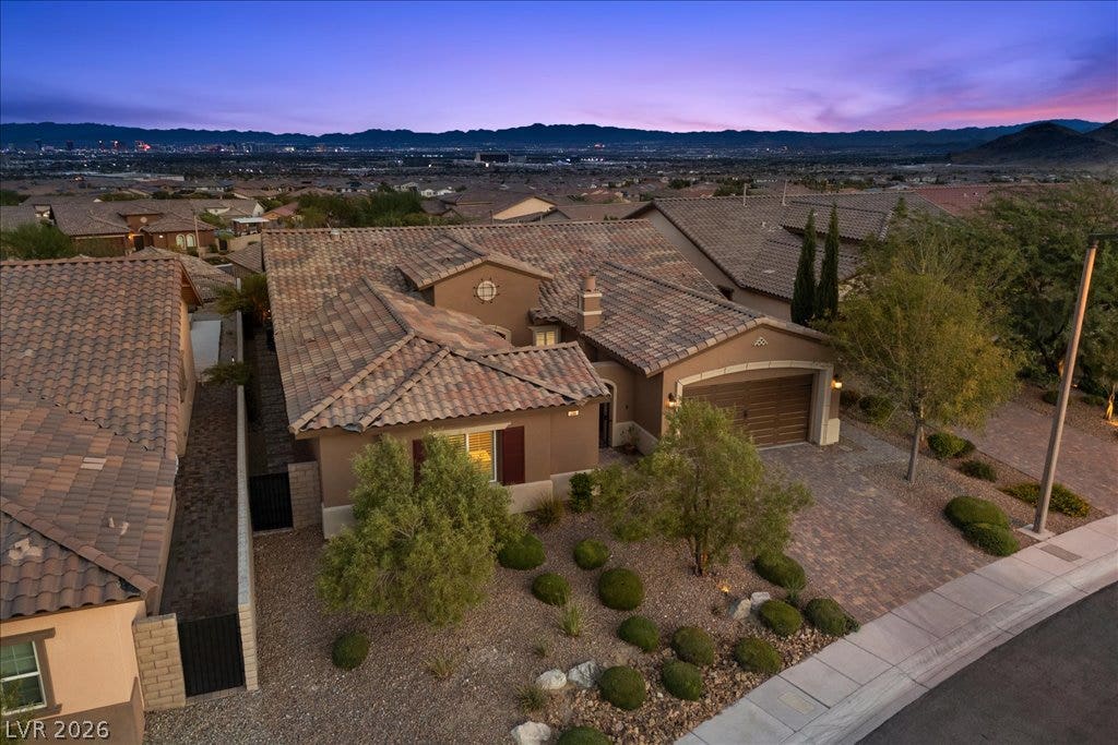 286 Besame Court, Las Vegas, NV 89138 Dusk skies frame this classic desert home featuring a tiled roof and paved driveway.