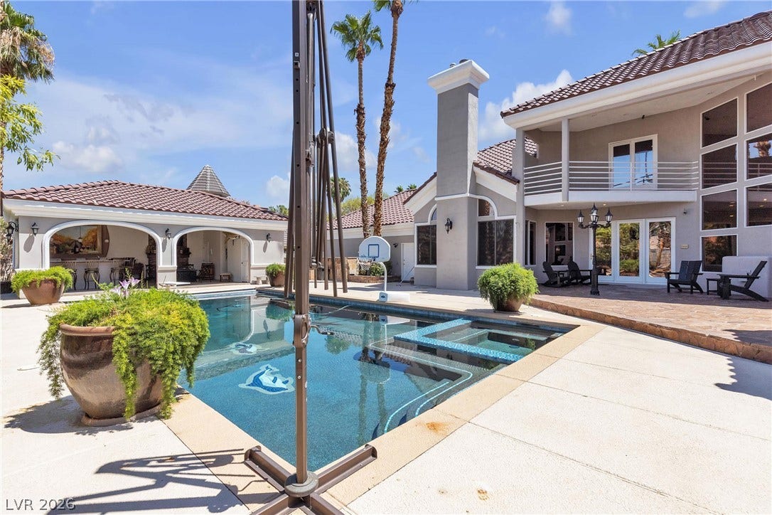 3341 Camino Gardens Way, Las Vegas, NV 89146 A tiled swimming pool and integrated spa anchor this Mediterranean-style backyard oasis under clear blue skies.