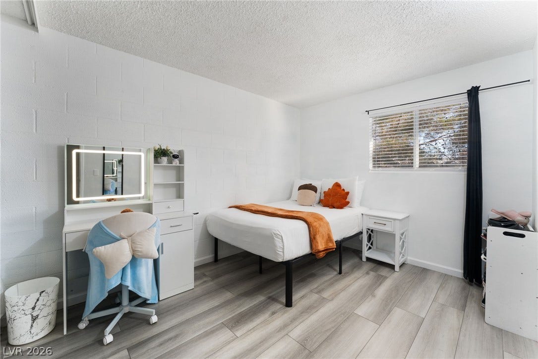 2515 Donna Street, #C, North Las Vegas, NV 89030 A sunny bedroom features modern plank flooring and a large window looking outdoors.